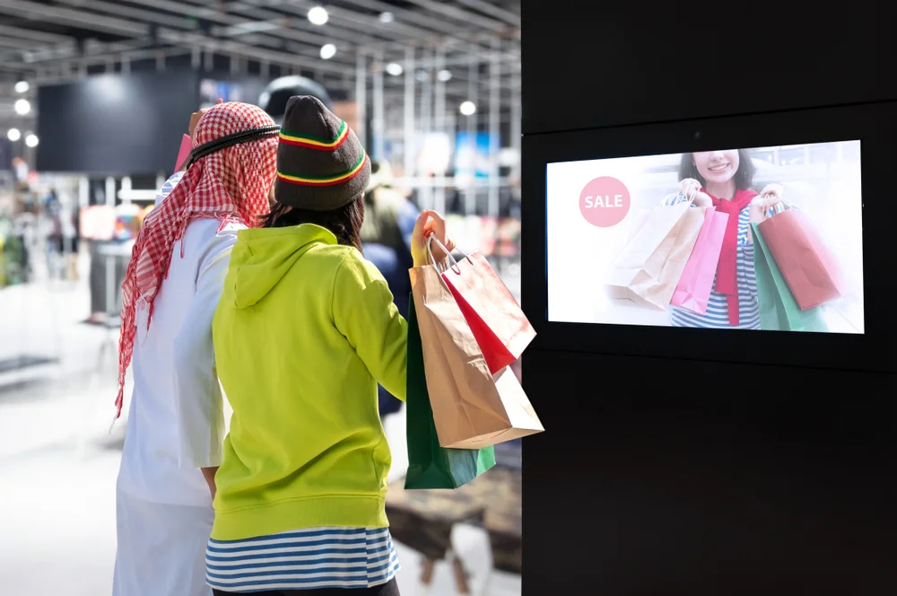Two people looking at a dooh ad on a mall